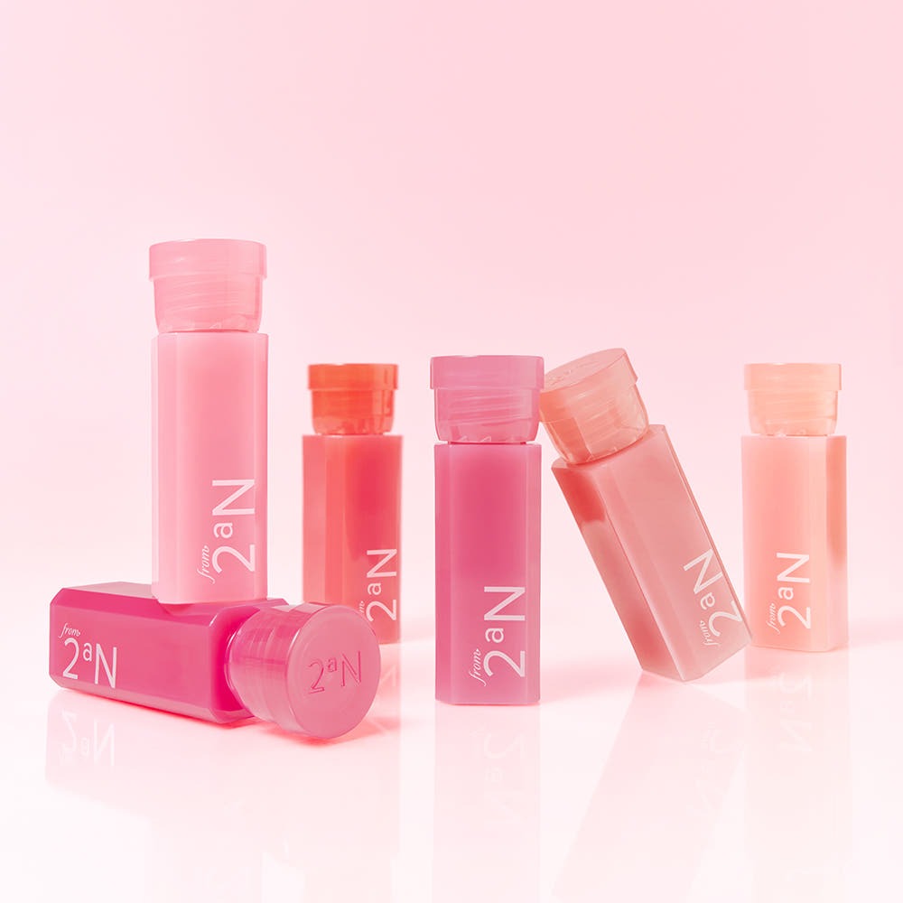 2AN Mini Glaze Bouncing Tint, produits de la marque 2AN, maquillage lèvres rose sur fond pastel rose, packaging en flacons.