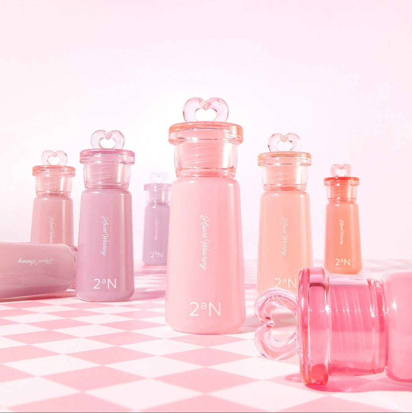 Collection de blush liquides 4.4g 2AN Heart Wearing Liquid Cheek sur fond rose, flacons élégants avec bouchons en forme de cœur.