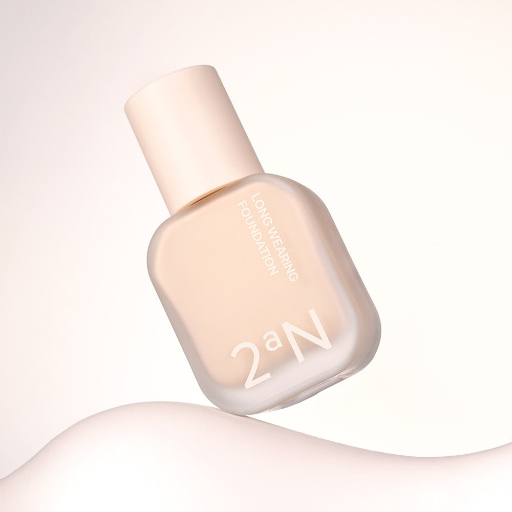 2AN Long Wearing Foundation 2AN, flacon sur fond clair, packaging maquillage lumière douce, studio beauté