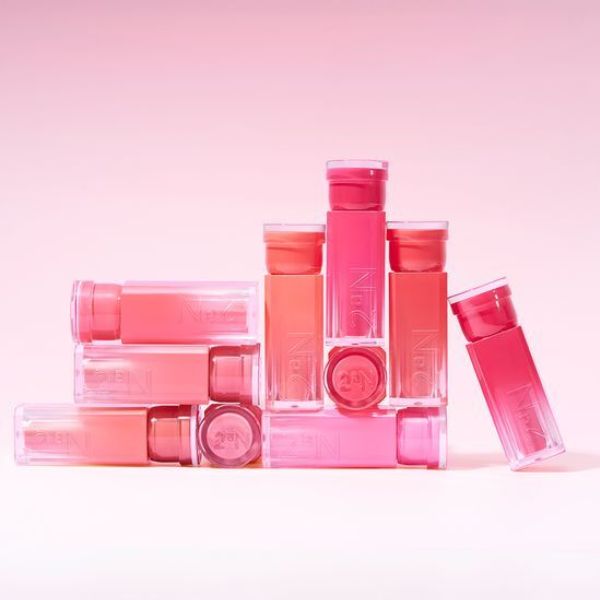 Décris l'image en français : 2AN Glaze Bouncing Tint 2AN, packaging lumineux rose sur fond clair, produits alignés.