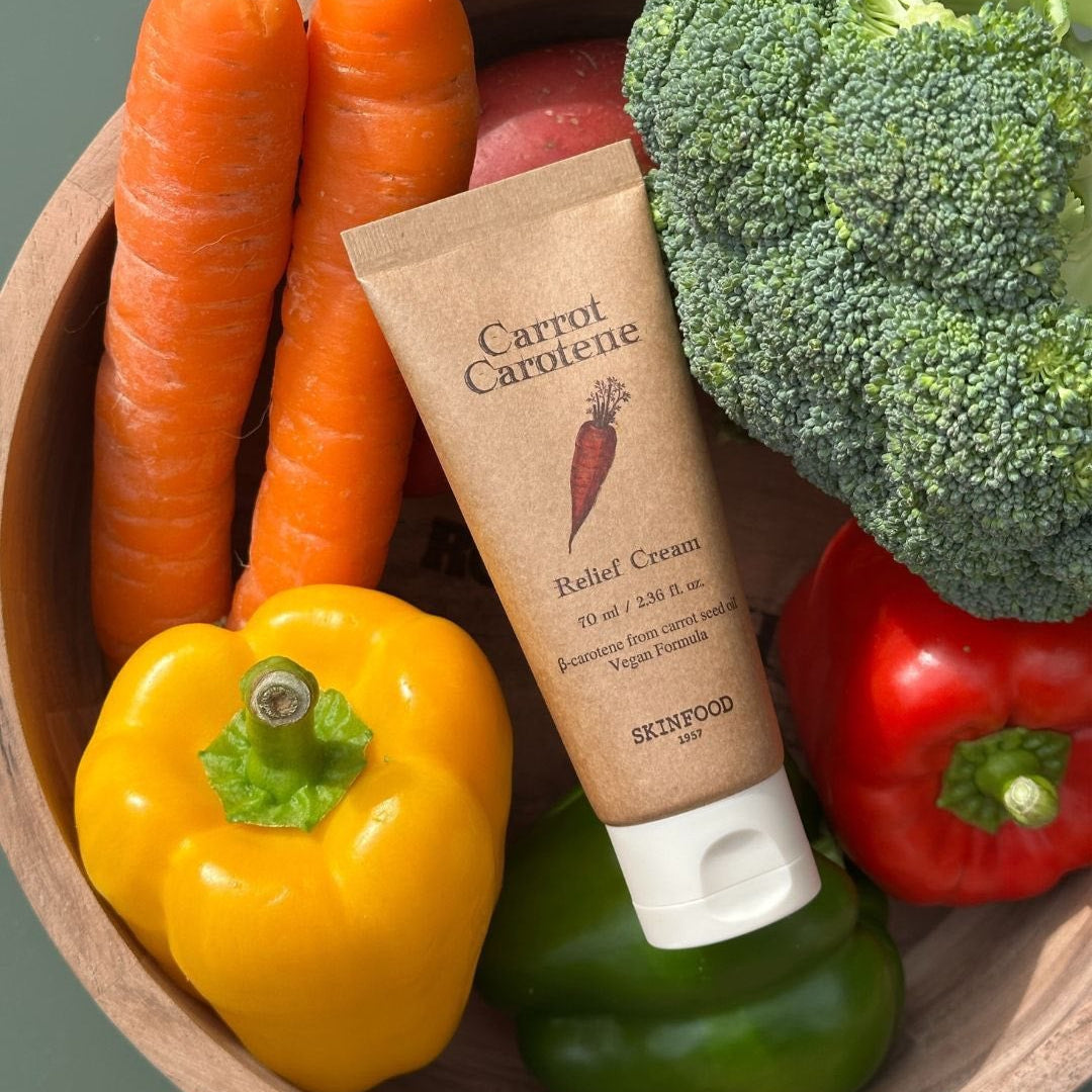 SKINFOOD Carrot Carotene Relief Cream 70ml, tube sur légumes (carottes, poivron) avec brocoli en arrière-plan.