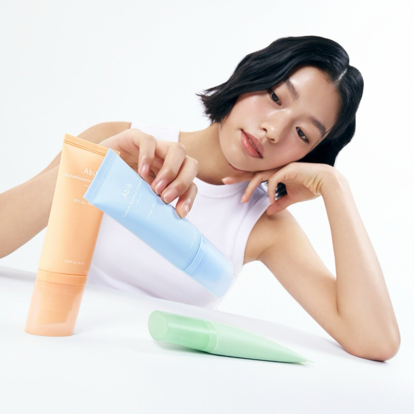 ABIB Sunscreen Tube 50ml 3 Types : tubes solaires ABIB sur fond clair, modèle tenant les produits, rendu photo.