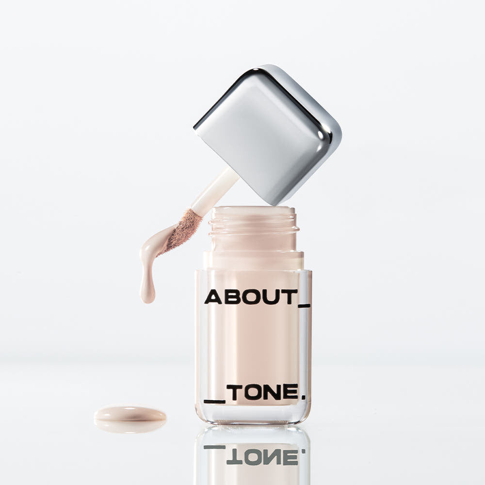 ABOUT TONE Skin Layer Cover Fit Concealer 5.6g, flacon distributeur et texture crème sur fond blanc.