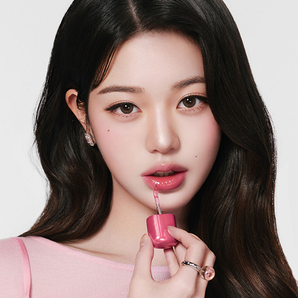 AMUSE Jel Fit Gloss de AMUSE, portrait beauté sur fond clair : jeune femme avec lèvres brillantes, tenue rose.