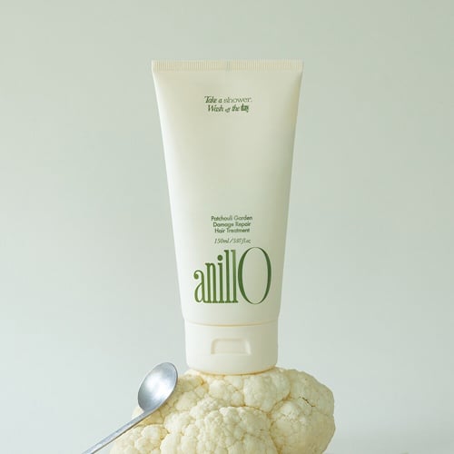 ANILLO Patchouli Garden Damage Repair Hair Treatment 150ml, tube crème sur fond clair avec accessoires salle de bain