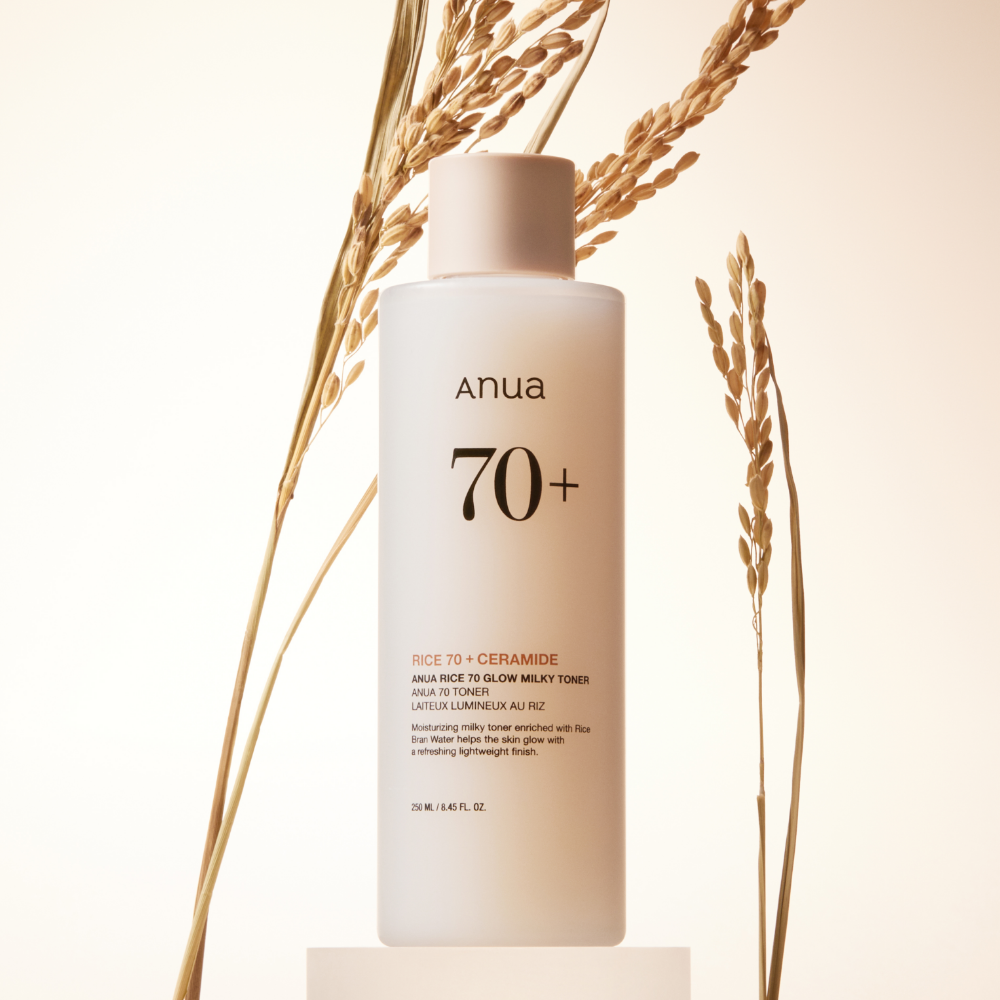 Décris l'image en français : ANUA Rice 70 + Ceramide Glow Milky Toner 250ml, bouteille blanche ANUA sur fond clair, avec épis de blé.