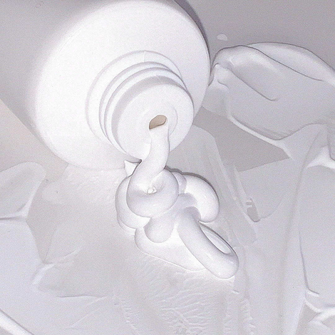 Crème AOU Tone-Up Dazzling Cream étalée sur une surface, montrant sa texture onctueuse et éclatante.