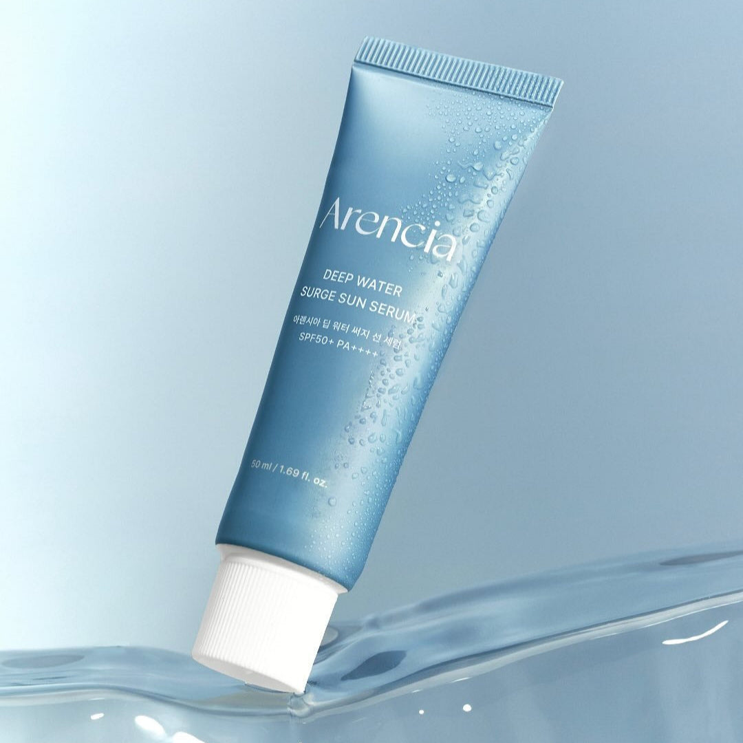 ARENCIA Deep Water Surge Sun Serum 50ml, tube bleu ARENCIA sur fond bleu, gouttes d’eau et ambiance solaire