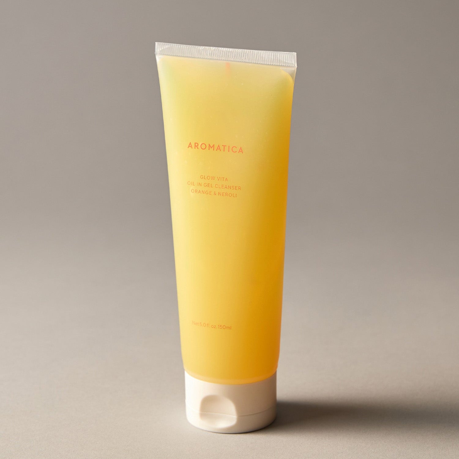 AROMATICA Glow Vita Oil-in-Gel Cleanser Orange & Neroli 150ML, tube jaune, sur fond beige, produit en gros plan.