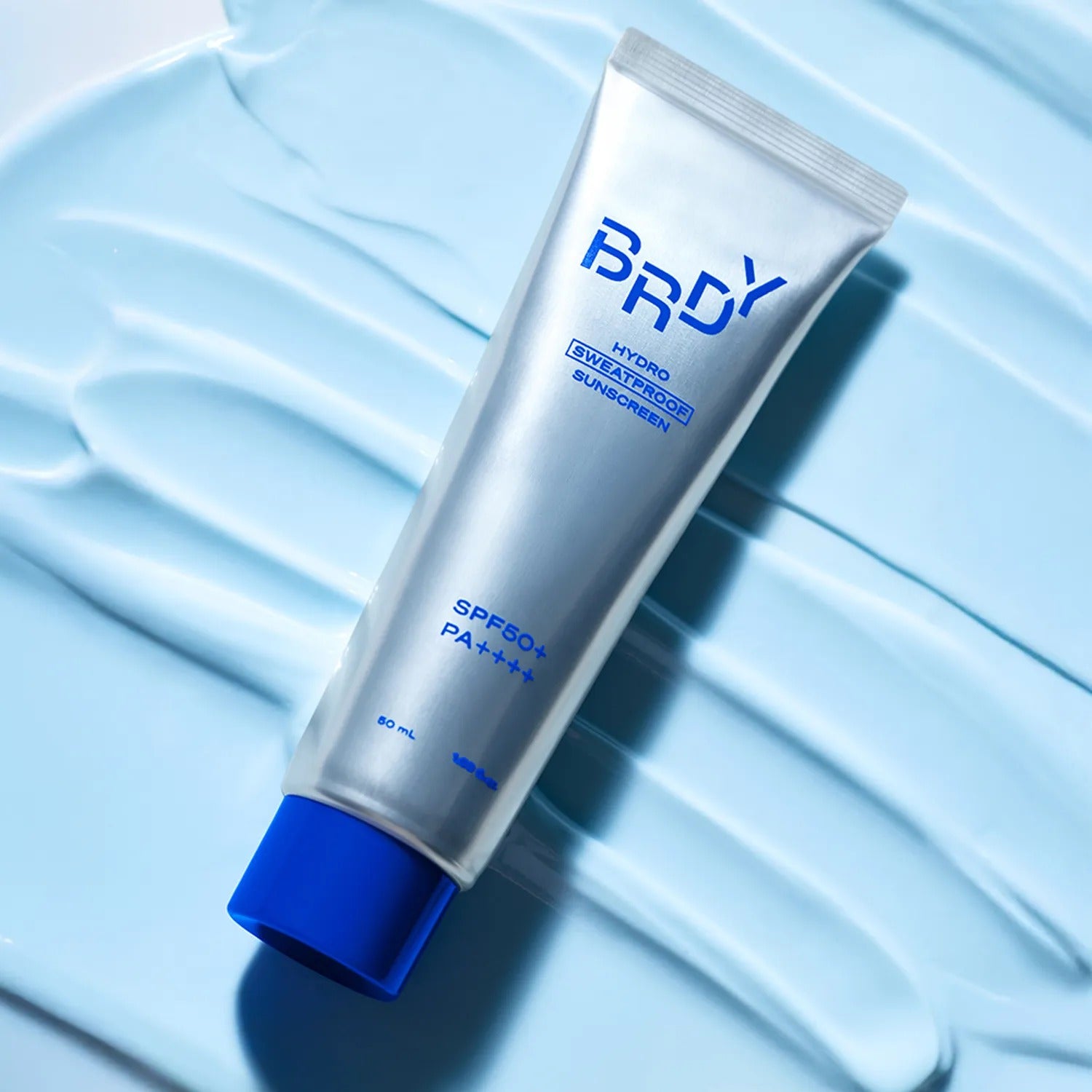 B.READY Hydro Sweatproof Sunscreen 50ml de la marque B.READY sur fond bleu, texture crème et contexte visuel solaire