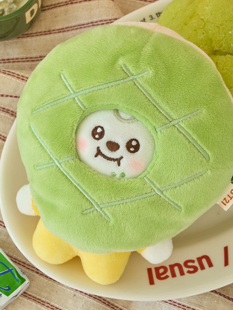 BT21 CHIMMY BABY COSTUME PLUSH DOLL BAKERY SHOP, peluche CHIMMY en costume bébé vert sur assiette, décor pâtisserie.