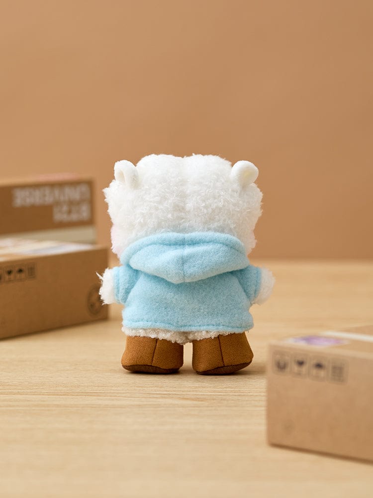 BT21 RJ minini DOLL BOOTS EDITION, peluche RJ alpaga en vêtement bleu, sur table avec boîtes BTS, décor chaleureux