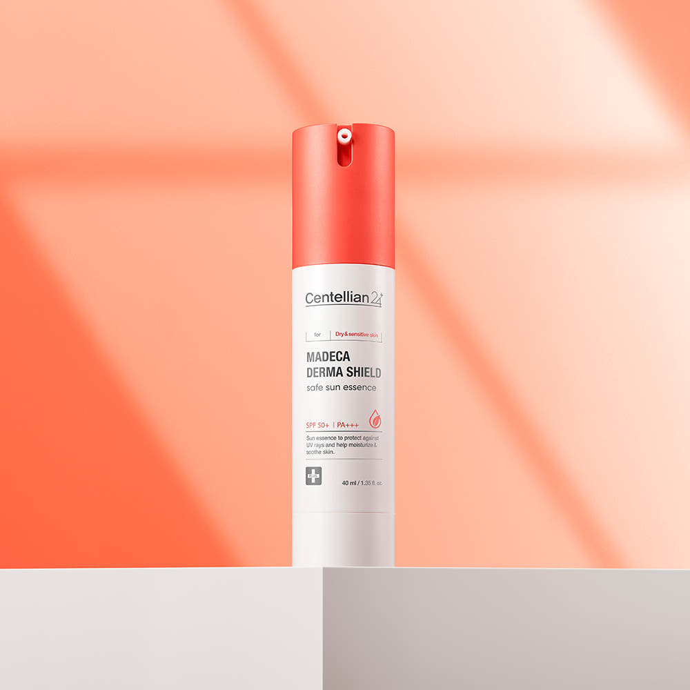CENTELLIAN 24 Madeca Derma Sheild Safe Sun Essence 40ml de Centellian 24 sur fond orange, flacon et lumière douce