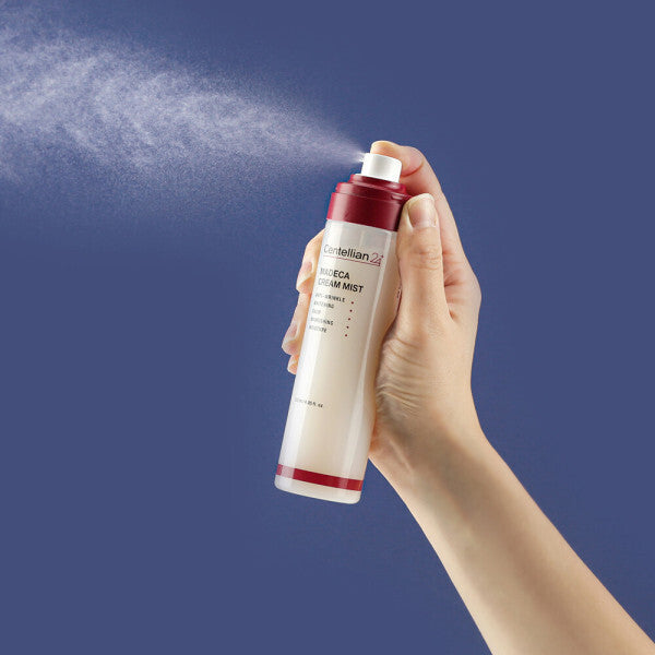 Main tenant CENTELLIAN 24 Madeca Cream Mist 120ml, flacon crème-mist sur fond bleu, produit de la marque