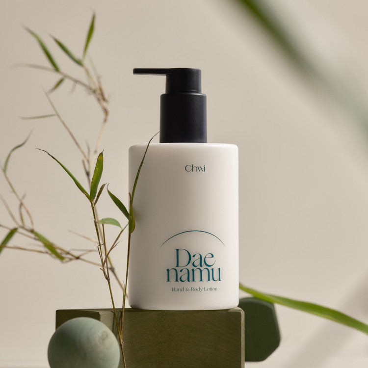 CHWI (CHI) Dae Namu Hand & Body Lotion 300ml, flacon sur support, feuilles et lumière naturelle, déco beauté.