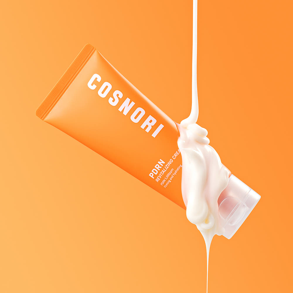 COSNORI PDRN Revitalizing Cream 70ml : tube orange et crème blanche, contexte visuel sur fond orange en studio.