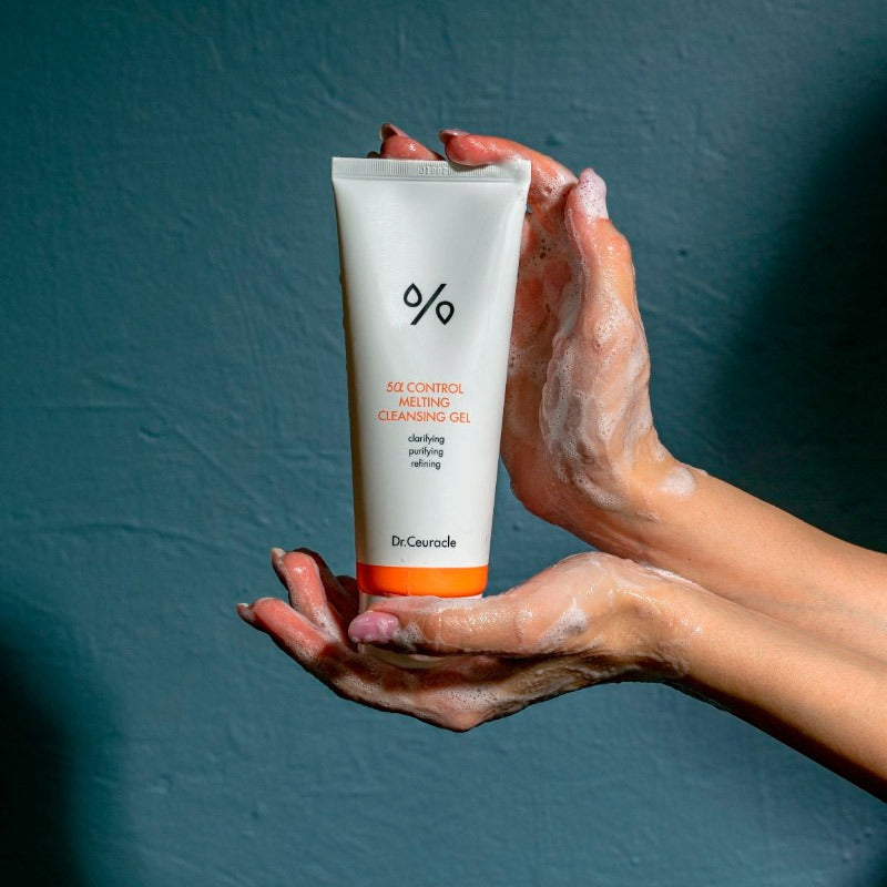 DR.CEURACLE 5 Alpha Control Melting Cleansing Gel 150ml, tube sur mains avec mousse, fond bleu, contexte beauté.