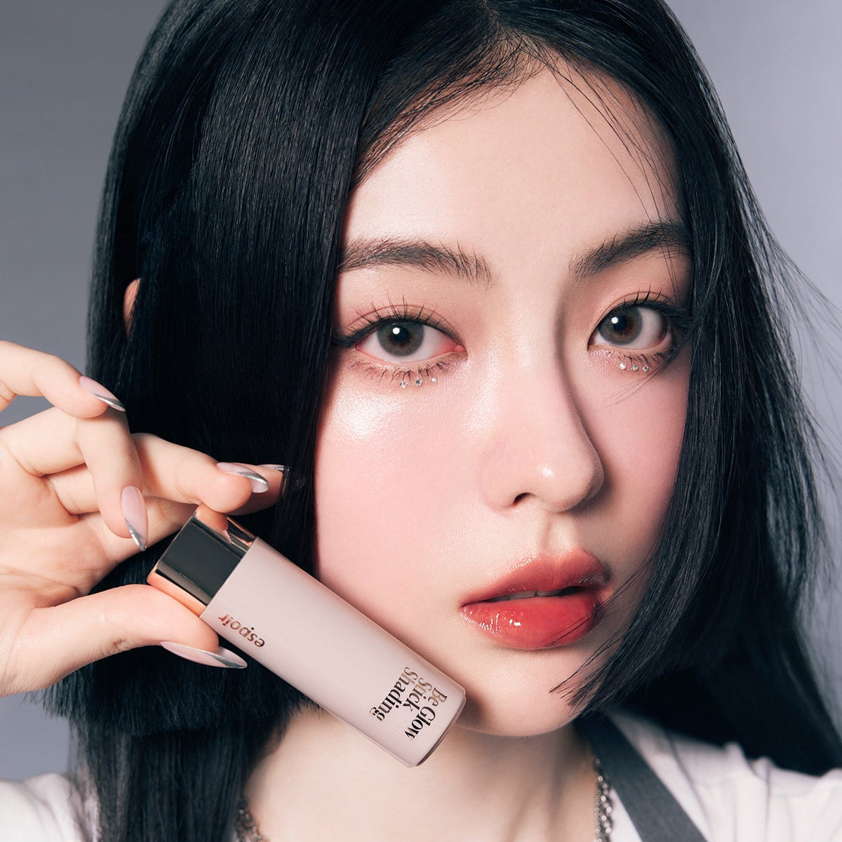 ESPOIR BE GLOW STICK SHADING, maquillage contour sur peau; femme aux cheveux noirs, main tenant le stick, fond studio.