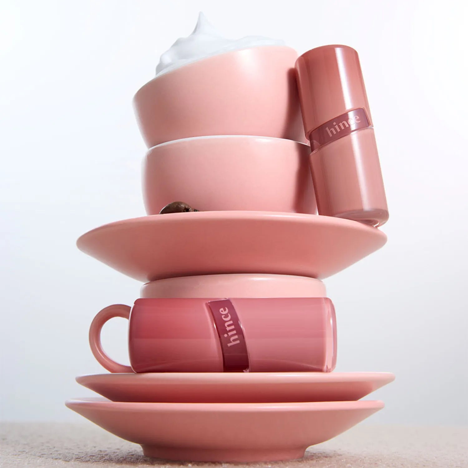 HINCE Low Glow Gel Tint posé sur des tasses roses, évoquant l'élégance et la douceur de ce produit cosmétique unique.