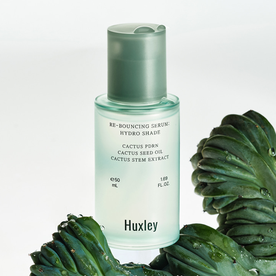 HUXLEY Rebouncing Serum Hydro Shade 50ml : flacon vert sur fond clair, plantes de cactus et feuilles, contexte beauté