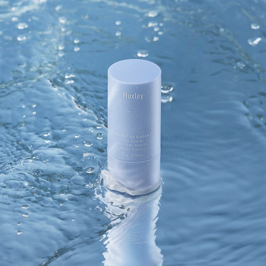 HUXLEY Sun Stick Watery Touch 20g, stick solaire Huxley sur l’eau bleue et éclaboussures, visuel rafraîchissant
