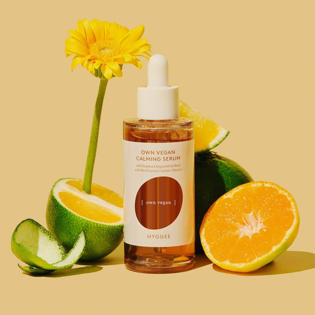 HYGGEE Own Vegan Calming Serum 50ml : flacon sur fond jaune, avec fleurs et agrumes, contexte beauté apaisante