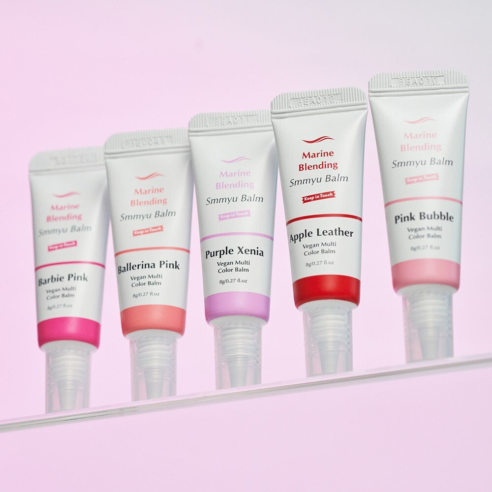 KEEP IN TOUCH Marine Blending Smmyu Balm, tubes de baume de la marque, sur fond rose pastel, contexte cosmétique.