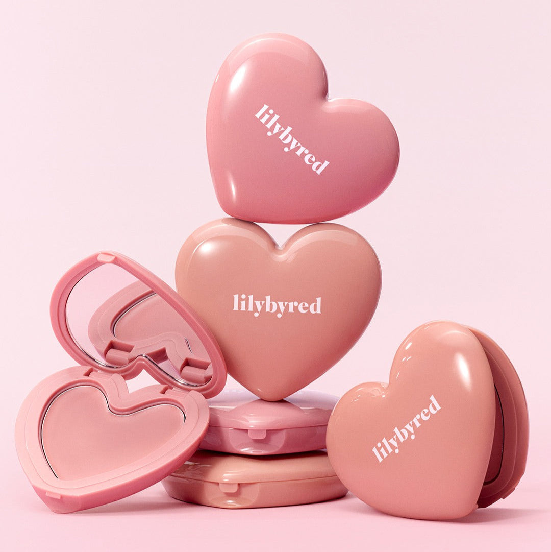 LILYBYRED Love Beam Cheek Balm de la marque LILYBYRED, packaging en forme de cœurs roses sur fond rose pastel.
