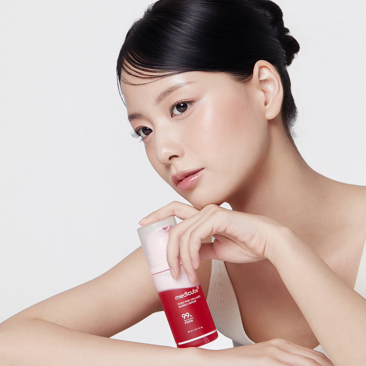 Jeune femme posant avec le MEDICUBE PDRN Bubble Cream Serum 95ml, révélant une peau éclatante et saine.