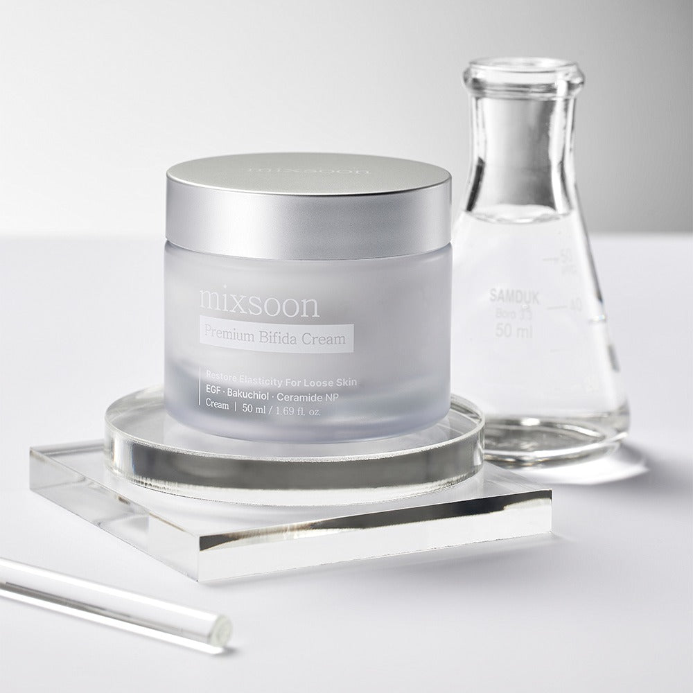 Décris l’image en français : pot MIXSOON Premium Bifida Cream 50ml et flacon, sur socle, fond blanc, esthétique beauté.