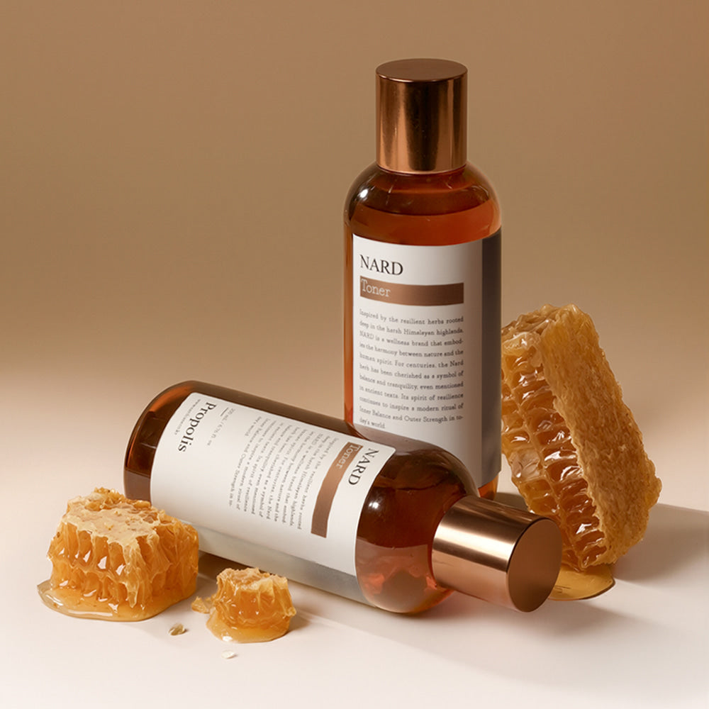 NARD Propolis Infusing Toner 200ml de NARD, bouteille brune sur fond beige avec morceaux de propolis à côté.