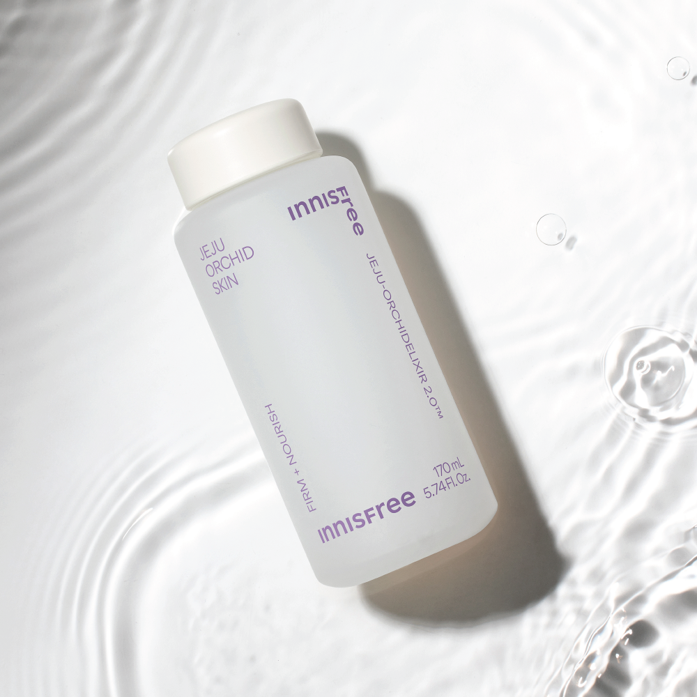 INNISFREE Jeju Orchid Skin 170ml de la marque Innisfree, flacon sur tissu blanc avec bulles d’eau, contexte visuel soin.