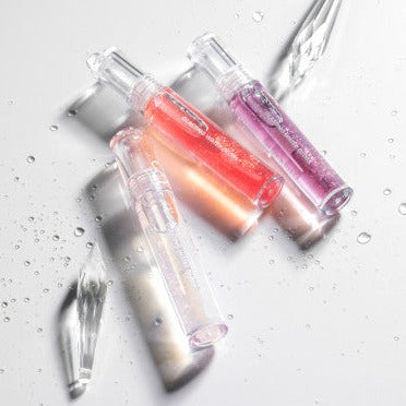ROMAND Glasting Water Gloss par la marque ROMAND, flacons givrées sur fond blanc avec éclaboussures d’eau et reflets