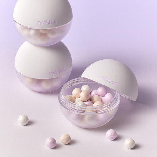 ROMAND Sheer Powder Pearls Powder, perles nacrées dans le couvercle, packaging mauve romand sur fond pastel violet.