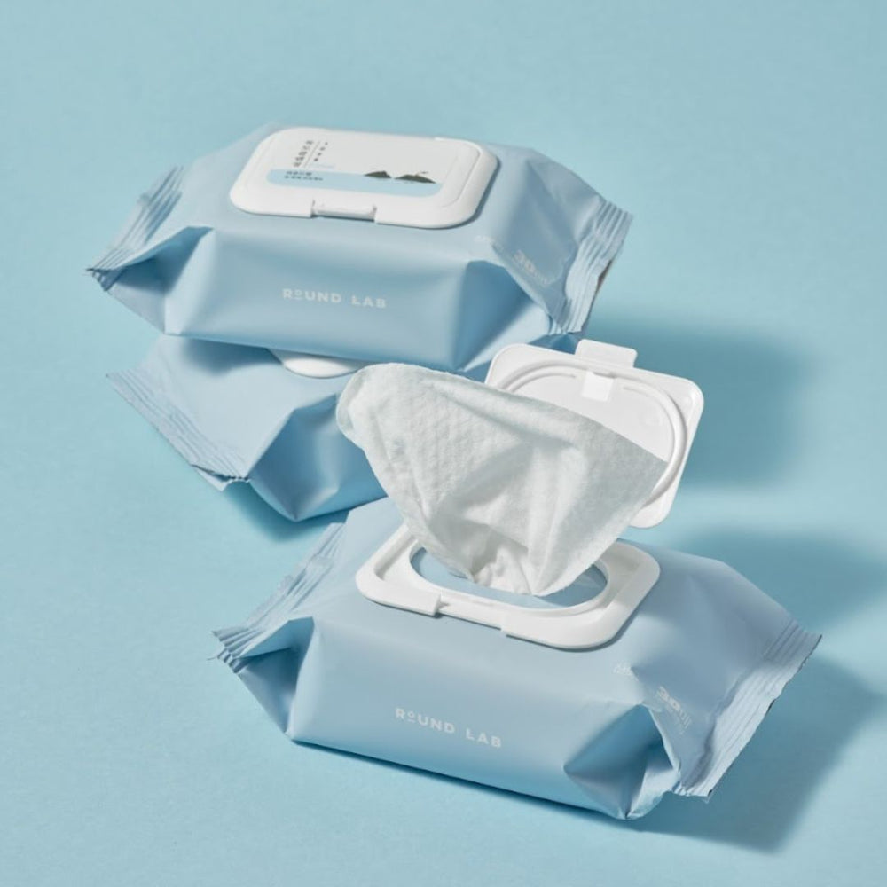 ROUND LAB 1025 Dokdo Cleansing Tissues de ROUND LAB, lingettes démaquillantes ouvertes sur fond bleu clair, en contexte beauté.