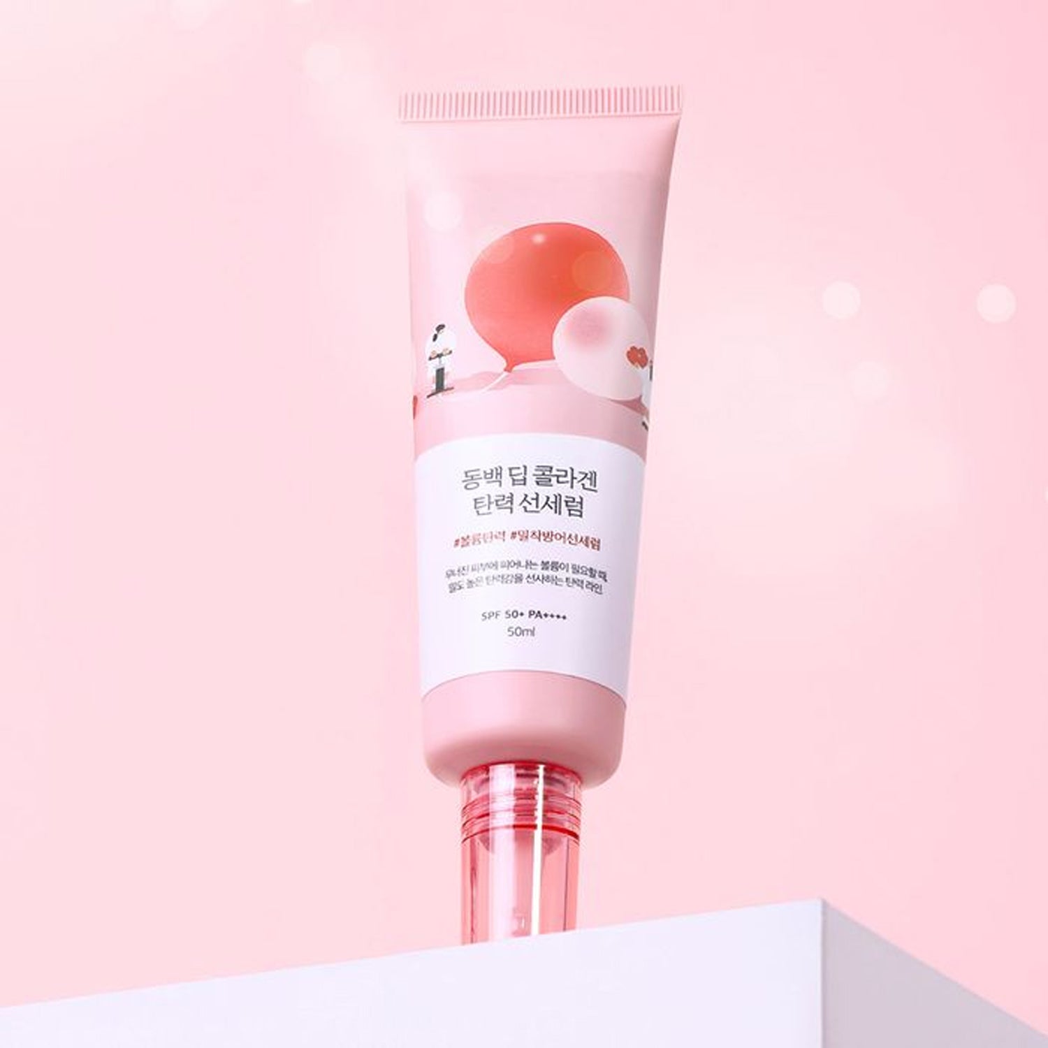 ROUND LAB Dongbaek Deep Collagen Elasticity Sun Serum 50ml, tube rose sur fond pastel, marque ROUND LAB visible.