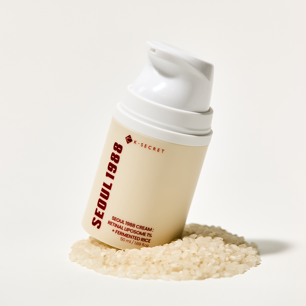 Décris l'image en français : SEOUL 1988 Retinal Fermented Rice Cream 50ml, flacon blanc sur riz fermenté, marque K-Secret.