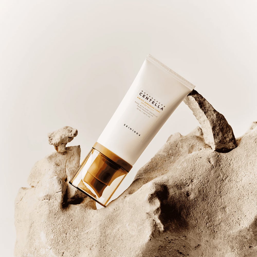 SKIN1004 Madagascar Centella Air-fit Sunscreen Light 50ml, SKIN1004, tube posé sur sol minéral beige.