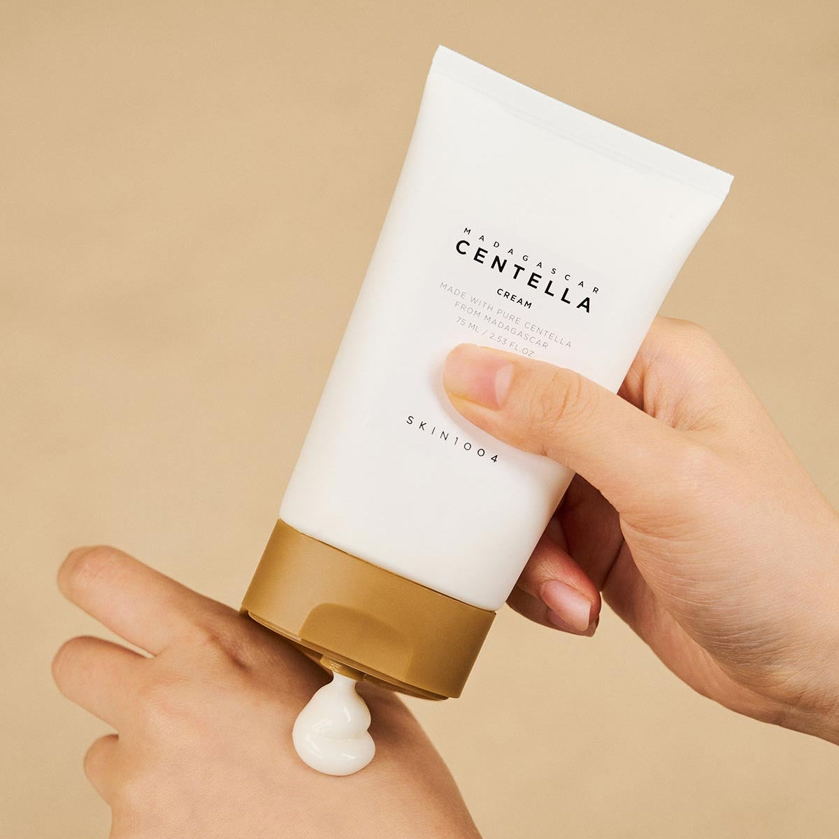 SKIN1004 Madagascar Centella Cream 75ml, crème Skin1004 en main sur fond beige, texture crème blanche.