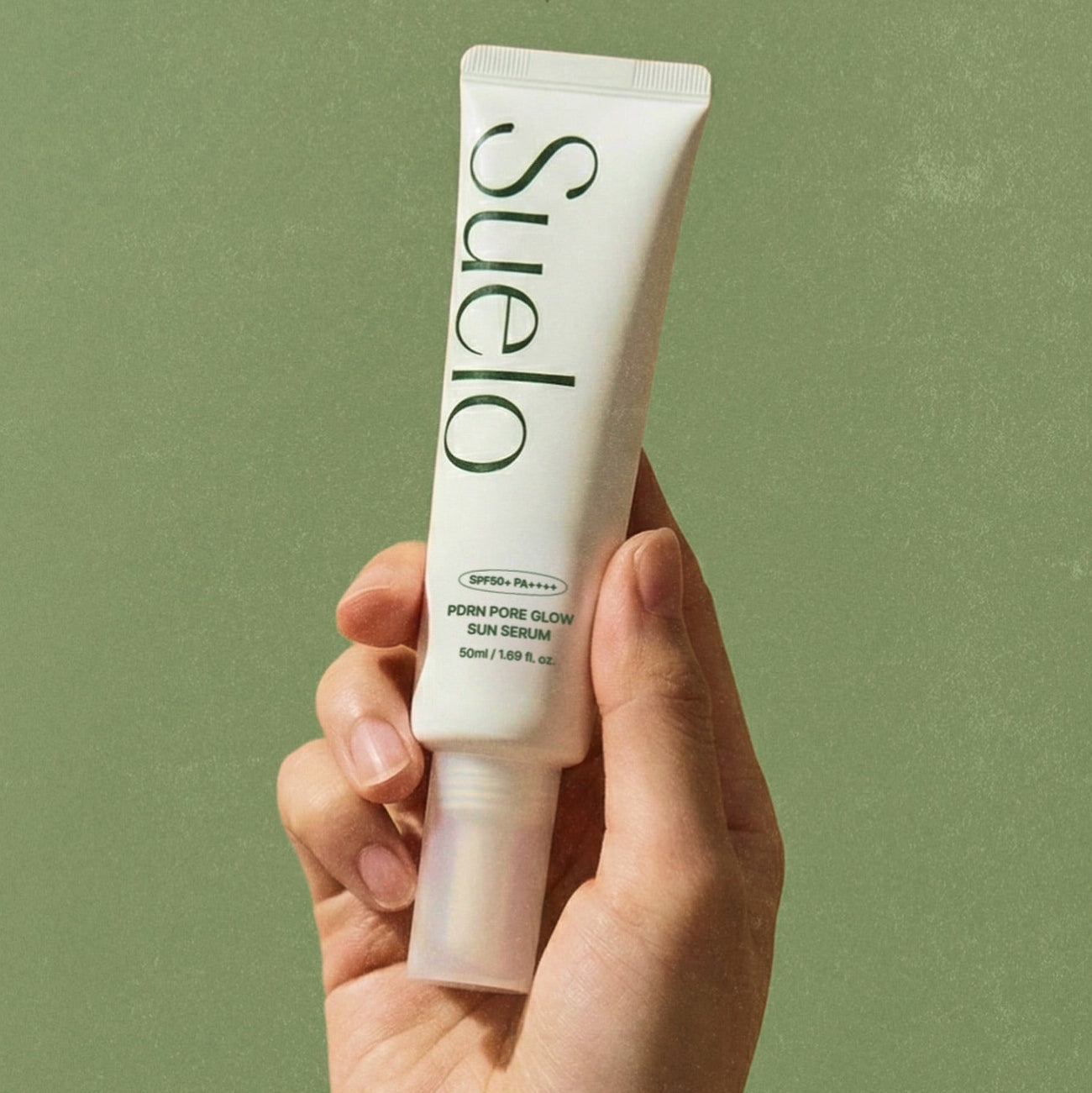SUELO PDRN Pore Glow Sun Serum 50ml en tube tenu sur fond vert, marque SUELO, contexte photo produit