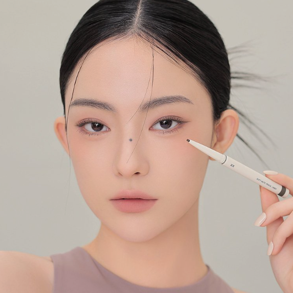 Décris l'image en français : 3CE Soft Mute Pencil Liner, maquillage des yeux sur visage, marque 3CE, produit en main.