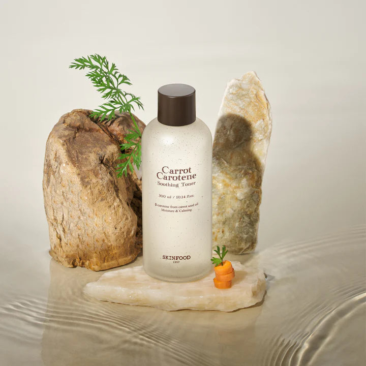 Décris l'image en français : SKINFOOD Carrot Carotene Soothing Toner 300ml de la marque SKINFOOD, avec carottes sur fond clair.