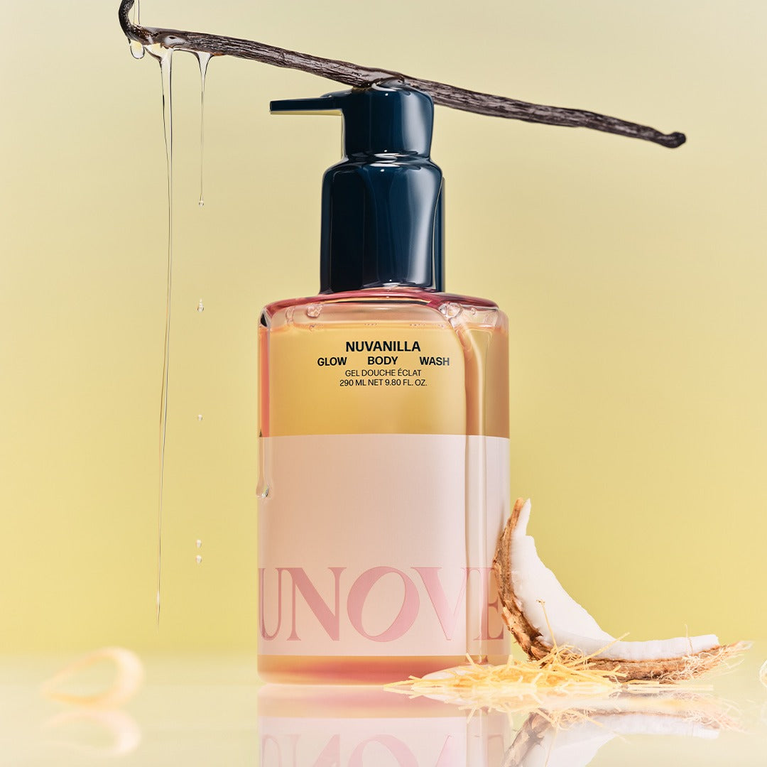 Bouteille de UNOVE Anove Glow Body Wash 290ml entourée de vanille et noix de coco, posée sur un fond jaune clair.