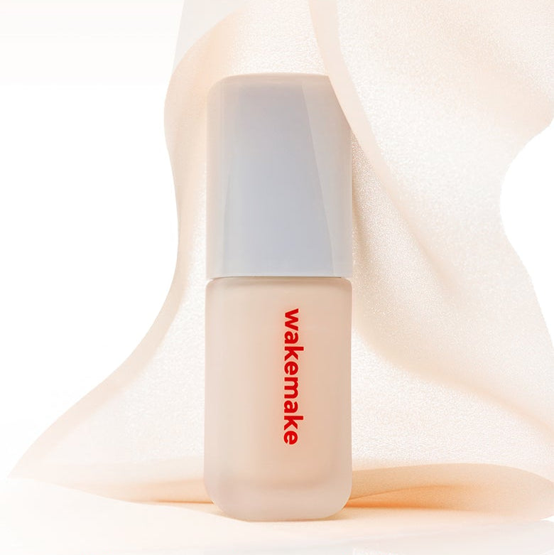 Flacon de WAKE MAKE Seamless Wear Foundation 30ml devant tissu blanc élégant.