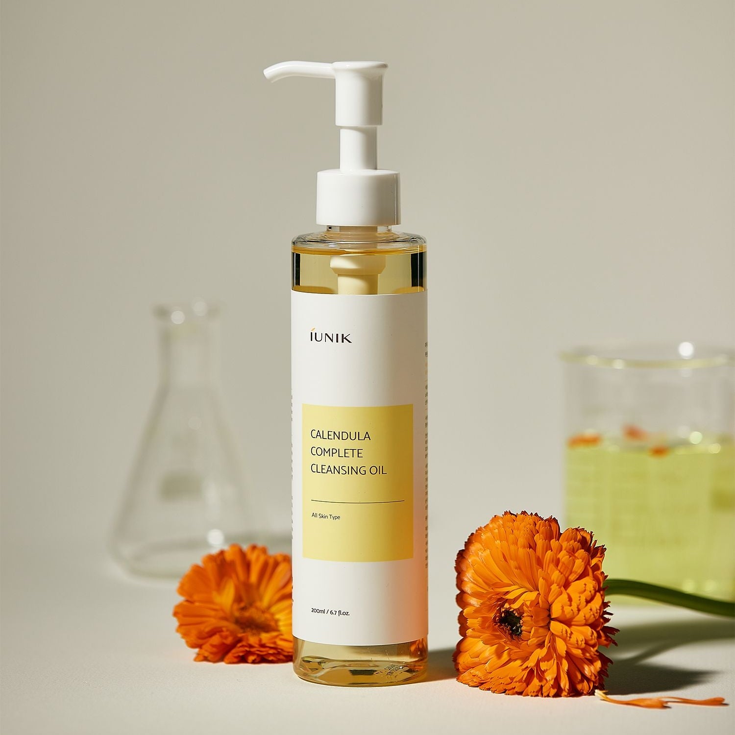 iUNIK Calendula Complete Cleansing Oil 200ml : flacon pompe, fleurs de calendula et huile sur fond clair, décor spa.