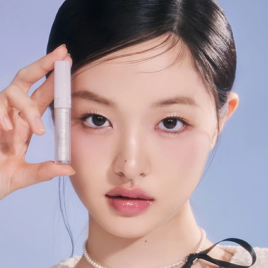 ROMAND The Universe Liquid Glitter par la marque : maquillage pailleté liquide, sur visage, main tenant le produit, fond bleu.