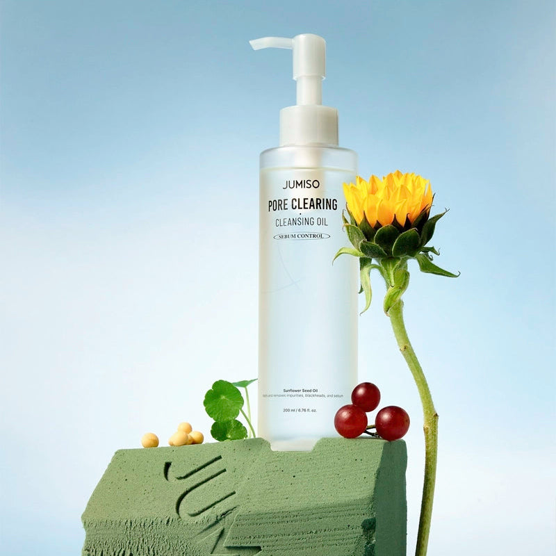 JUMISO Pore Clearing Cleansing Oil 200ml, flacon blanc sur socle vert avec fleurs et baies, fond bleu, marque JUMISO