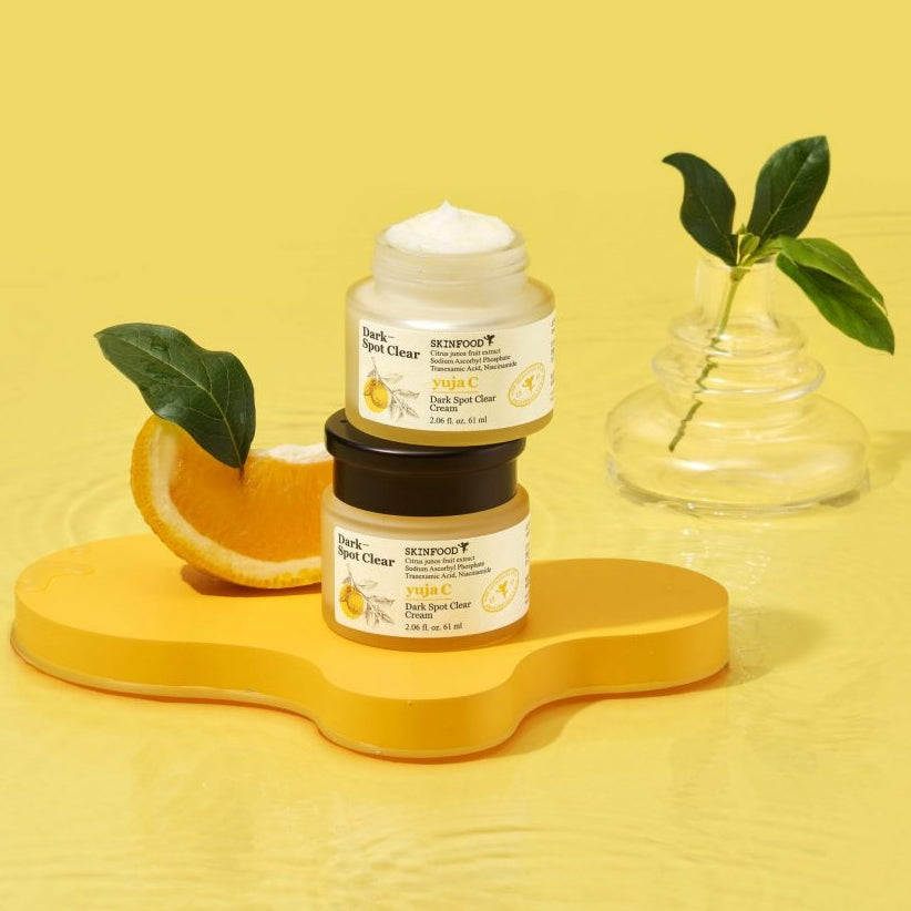 SKINFOOD Yuja C Dark Spot Clear Cream 70ml de SKINFOOD, pot de crème sur fond jaune avec feuilles et agrumes.