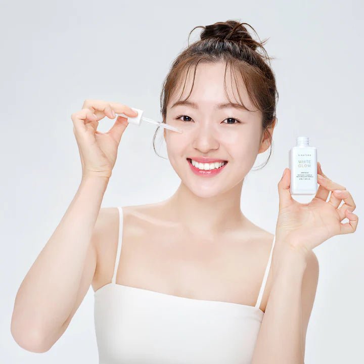 S.NATURE White Glow Ampoule 50ml : flacon S.NATURE présenté par une femme en salle de beauté, fond clair