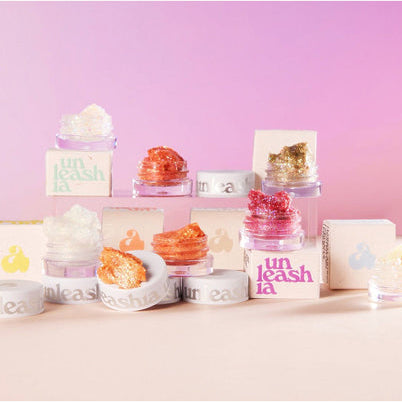 UNLEASHIA Get Loose Glitter Gel (#01 to #07) : pots de glitter en dégradé, fond rose, marque UNLEASHIA visible.
